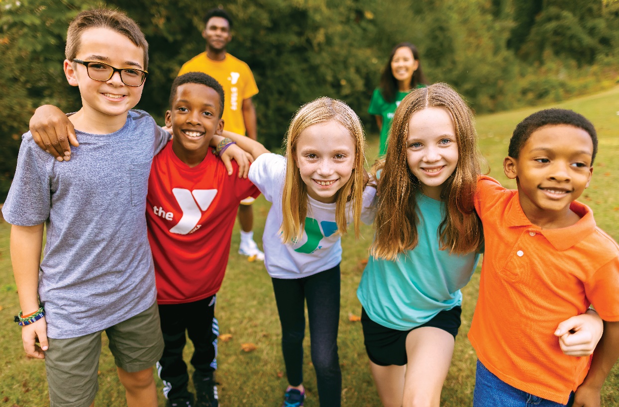 A diverse group of smiling children posing outdoors at an Owen County YMCA event, exemplifying the spirit of community and friendship fostered by the YMCA programs.