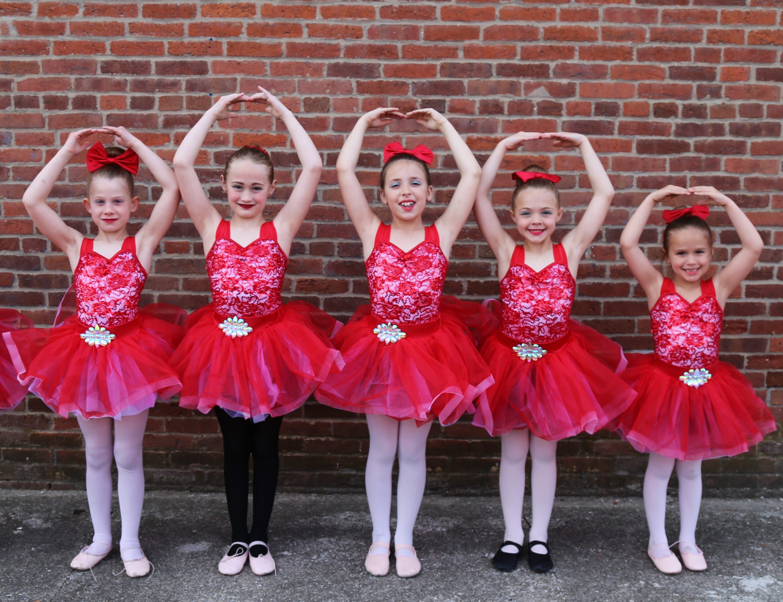 Ballet Tap group posing in red tutus against a brick wall