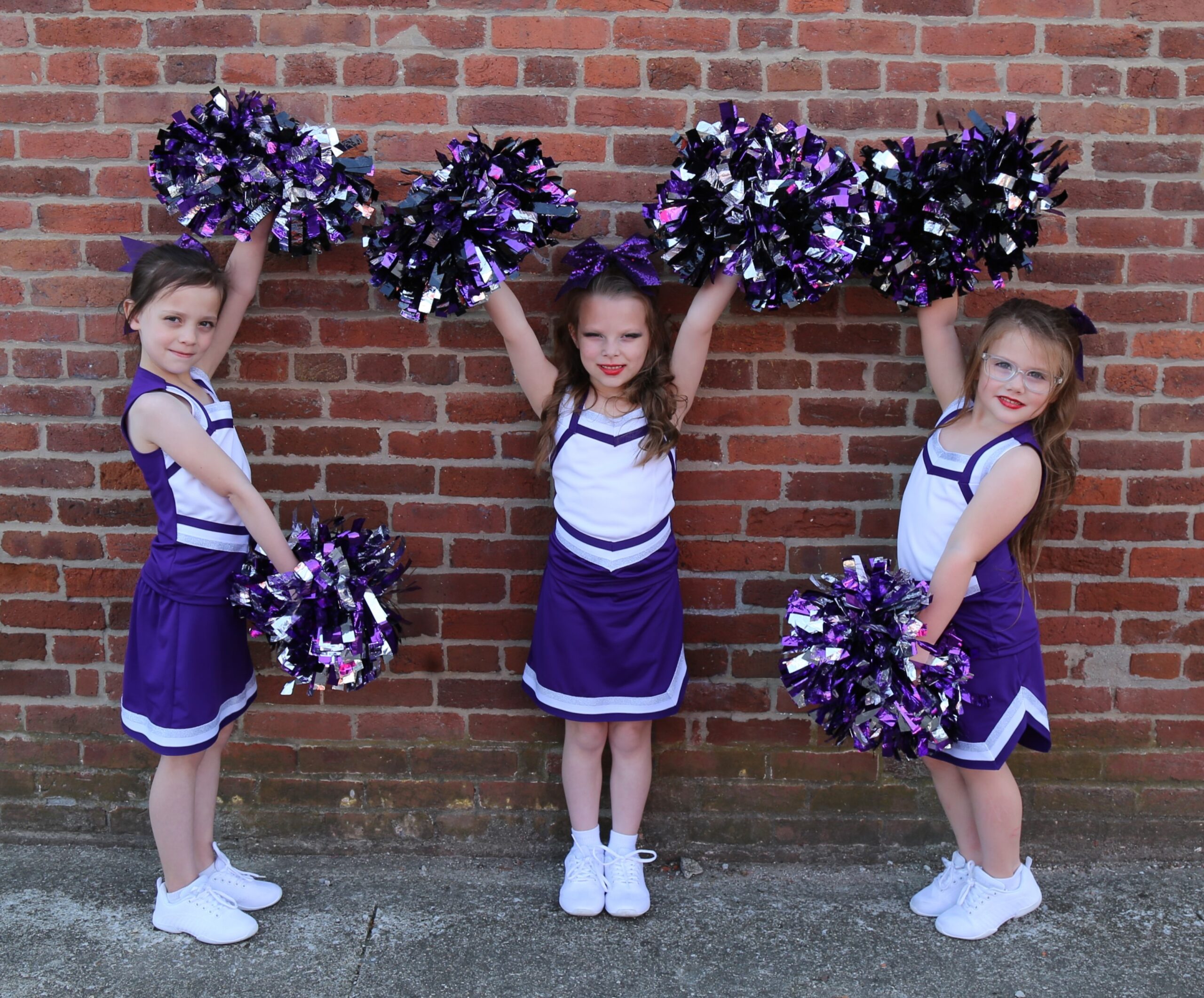 Sparkling Spinners cheerleading group posing against a brick wall
