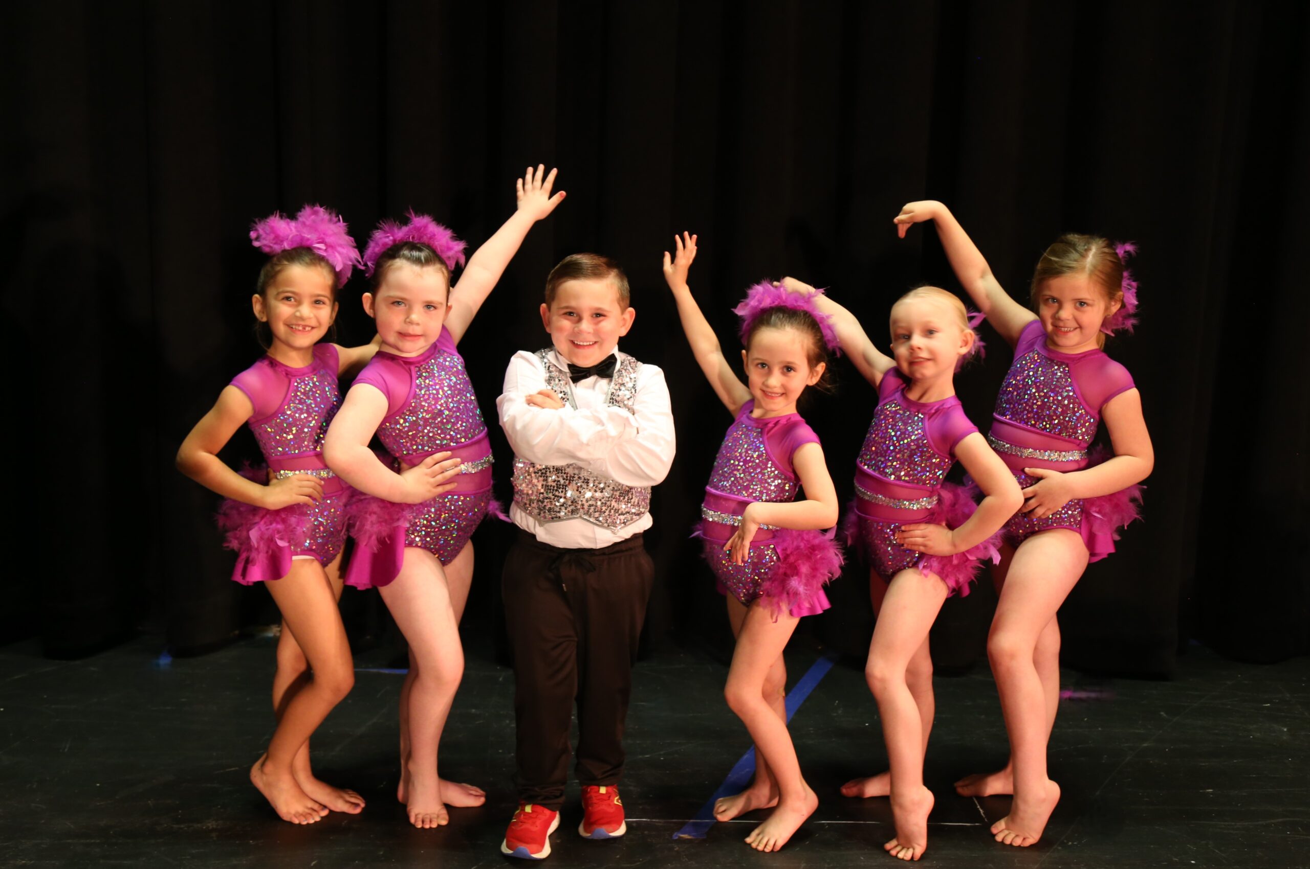 Little Flipsters dance group posing on stage in purple outfits